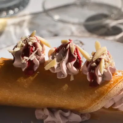 Dessert maison : biscuit roulé, crème à la framboise et amandes effilées