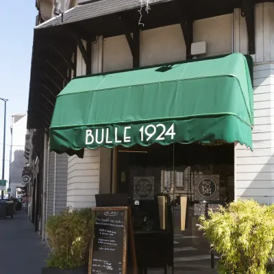 L'entrée du restaurant sous le store vert Bulle 1924