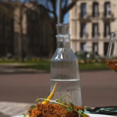 Assiette servie en terrasse, carafe d'eau et vue sur la place