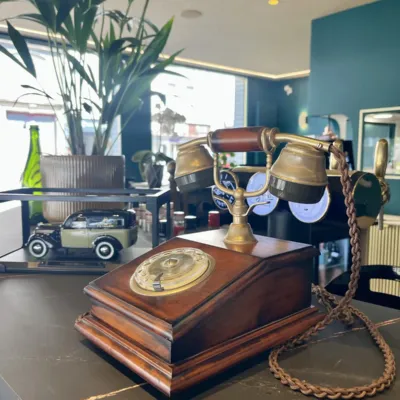 Téléphone ancien en bois et laiton posé dans la salle, clin d'œil aux Années folles